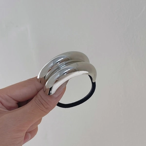 Nahaufnahme einer silbernen Metallschnalle an einem schwarzen elastischen Haargummi