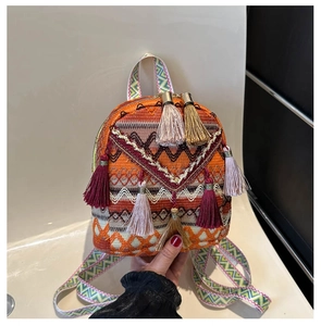 Detail of a colorful woven mini backpack with geometric patterns and tassel accents