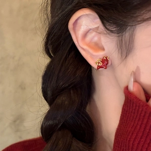 Gold plated red dragon earrings worn by a model with warm lighting for festive look