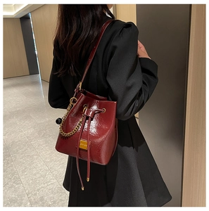 Détail du sac seau bordeaux en cuir plissé brillant avec décorations de chaîne dorée