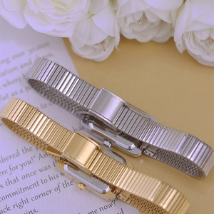 Detail of silver and gold stainless steel elastic watch bands on a floral background
