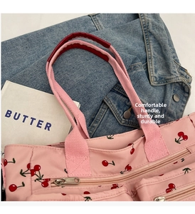 Detail of printed tote bag featuring cherry patterns and durable reinforced handles