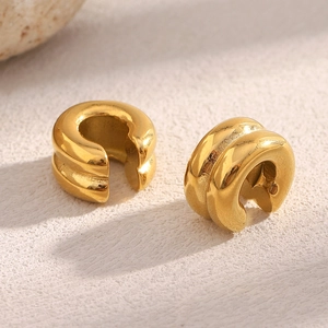 Detailed view of gold plated double-layer ear cuffs on a minimalist beige stone background