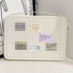 Close-up of inspirational quote stickers on a cream laptop sleeve with zipper detail