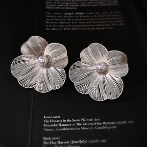 Boucles d'oreilles fleur en métal avec perle sur fond de livre artistique