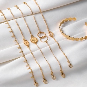 Detail view of 6-piece gold charm bracelet set featuring shells and embossed coin charms