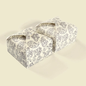 Detailed view of two mini paisley pattern gift boxes in cream and navy blue finishes