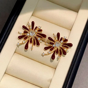 Macro shot of wine red enamel firework earrings with clear zircon stones in a velvet box