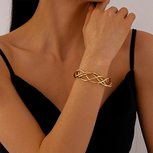Detail shot of a twisted gold mesh geometric open bangle on a model's wrist