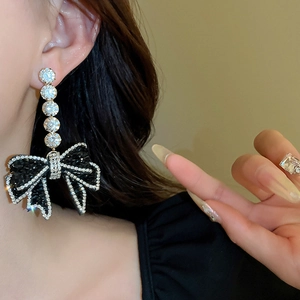 Macro shot of long drop earrings featuring a black bow and brilliant zircon stones