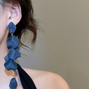 Detail view of blue acrylic petal tassel earrings worn by a model on a clean background