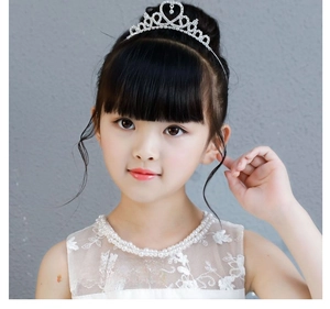 Close-up of a silver princess crown with heart-shaped rhinestones and a pearl necklace