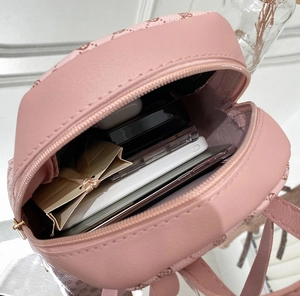 Internal view of mini pink backpack showing storage capacity for phone and cosmetics