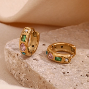 Détail de boucles d'oreilles huggie dorées 18K avec zircons colorés sur socle en pierre