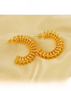 Macro detail of gold-plated titanium steel hoop earrings with spiral twist design