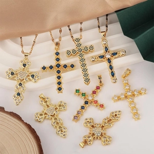 Cross pendant necklaces in gold finish with zircon stones on silk and wood background