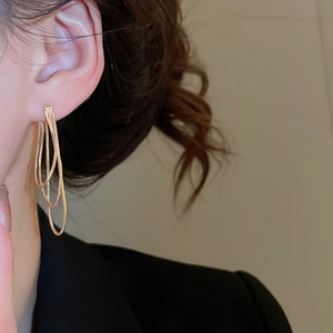 Gros plan de boucles d'oreilles élégantes à triple chaîne dorée portées par un mannequin