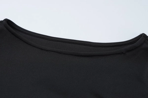 Close-up of the black knit dress showing the round neck detail and ribbed fabric texture