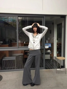 Outdoor street style shot of white zip-up hoodie and grey high-waist wide-leg knit trousers