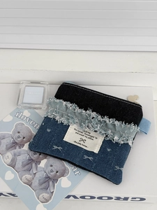 Close-up of denim cosmetic bag with raw edge frayed patchwork and logo label details