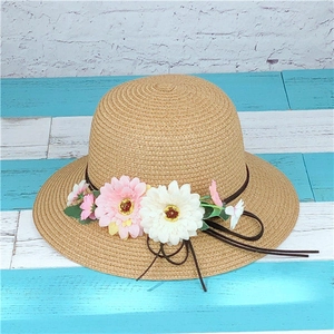 Detail of the woven straw sun hat featuring pink daisies and a delicate ribbon bow