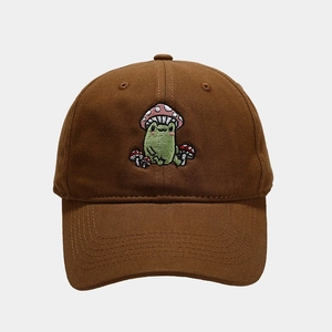 Close-up of cute green frog and mushroom embroidery on brown cotton baseball cap