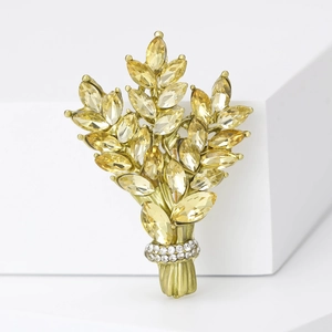 Detailed close-up of a golden wheat brooch with yellow crystals on a white stand