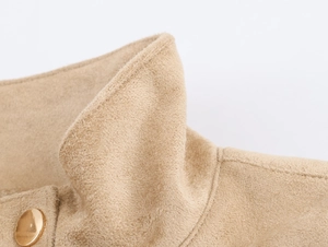 Détail du col en daim beige avec un bouton rond en métal doré de qualité supérieure