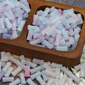 Macro shot of 6x12mm pink and blue gradient glass bamboo tube beads in a wooden tray
