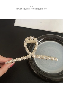 Détail de la grande pince à cheveux en métal doré avec perles élégantes et strass brillants