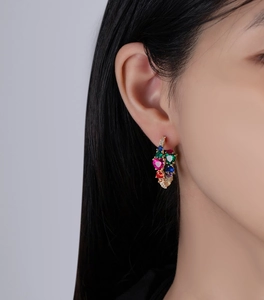 Close-up of model wearing heart-shaped earrings with colorful pavé-set cubic zirconia