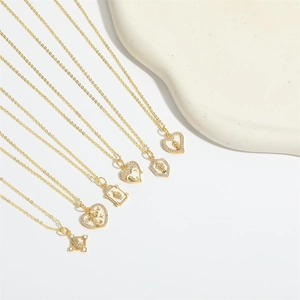 Flat lay of multiple gold necklaces with diverse heart and geometric pendants on white stone