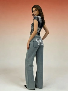 Dettaglio della stampa a farfalla bianca sulla tasca posteriore dei jeans blu chiaro