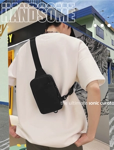 Detailed view of the black canvas chest bag worn on back against urban street background
