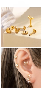 Dettaglio di piercing in titanio dorato con design a stella, cuore e luna in un set
