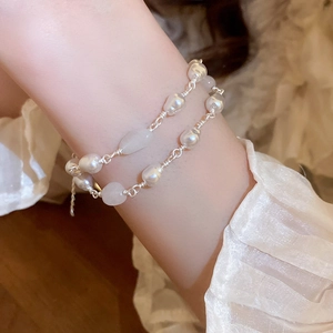 Close-up of double-layered freshwater pearl and jade tassel bracelet on a wrist