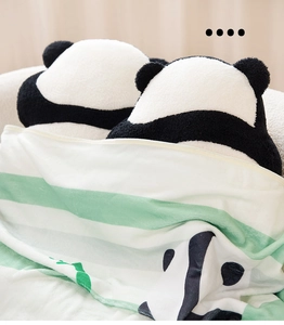 Nahaufnahme von Plüsch-Panda-Kissen und einer Streifendecke in gemütlicher Umgebung