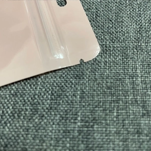 Detail of pink plastic packaging bag showing tear notch and resealable zip lock closure