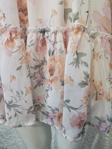 Détail de l'ourlet en mousseline à volants avec imprimé floral rose et orange sur blanc