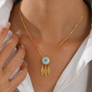 Gold stainless steel evil eye necklace with three delicate feather charms on a model