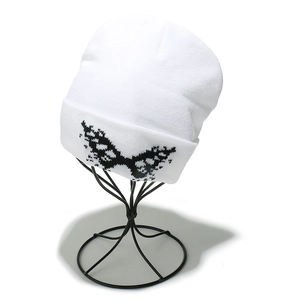 Detailed close-up of white knit beanie featuring black pixelated butterfly embroidery