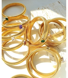 Detail of gold-plated gas pipe elastic bracelets with rectangular emerald-cut zircons