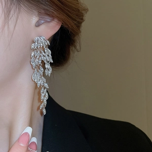 Close-up of silver tassel earrings with leaf design and shimmering crystals on model