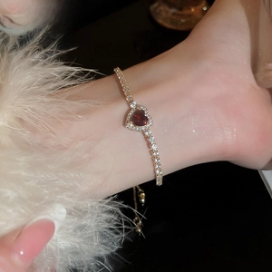 Close-up of heart-shaped red gemstone bracelet with micro-pave diamonds on wrist