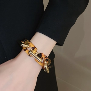 Dettaglio del bracciale a maglie in tartaruga e anelli dorati indossato dal modello