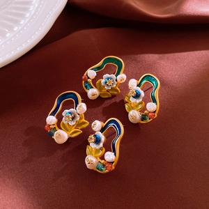 Detailed macro view of baroque enamel flower earrings with pearls on silk background