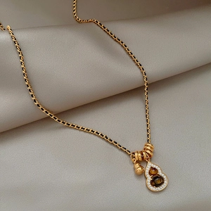 Detail of 18K gold plated gourd necklace with tiger eye stone and pavé zircon settings