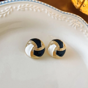 Detailed macro shot of vintage black and white enamel button earrings on a ceramic dish