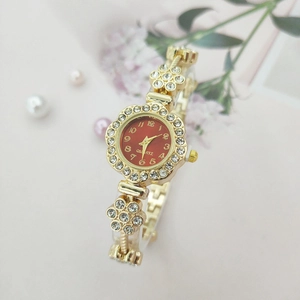 Detailed view of women's gold floral watch with red dial and sparkling rhinestones