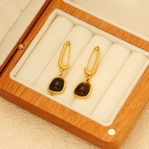 Elegant gold earrings with irregular brown gems in a beige velvet jewelry box
